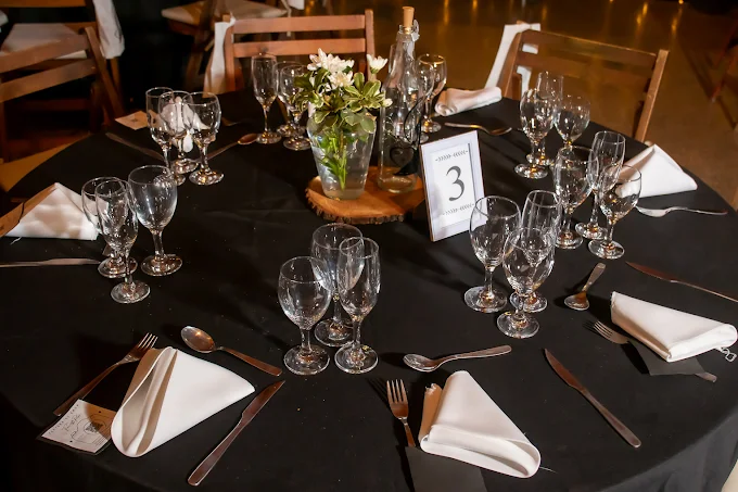 Mesa redonda con mantel negro, copas y servilletas blancas, lista para la cena