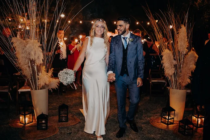 Los novios salen de la mano entre invitados con bengalas